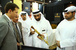 The Secretary General of the Executive Council, H.E. Mohammed Ahmed Al Bowardi, examines a half size Kalashnikov, gold plated.